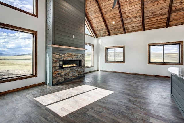 unfurnished living room featuring dark wood-type flooring, a stone fireplace, beamed ceiling, high vaulted ceiling, and wood ceiling