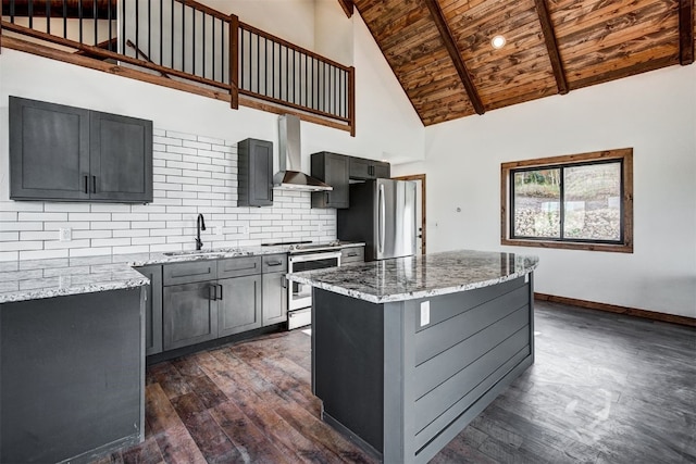 kitchen featuring decorative backsplash, appliances with stainless steel finishes, sink, wall chimney range hood, and a center island