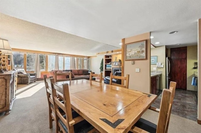 dining space featuring light colored carpet and a textured ceiling