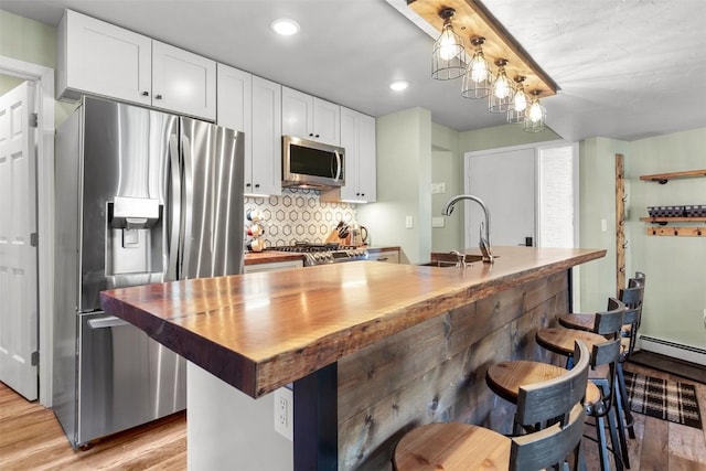 kitchen with pendant lighting, white cabinetry, sink, and stainless steel appliances