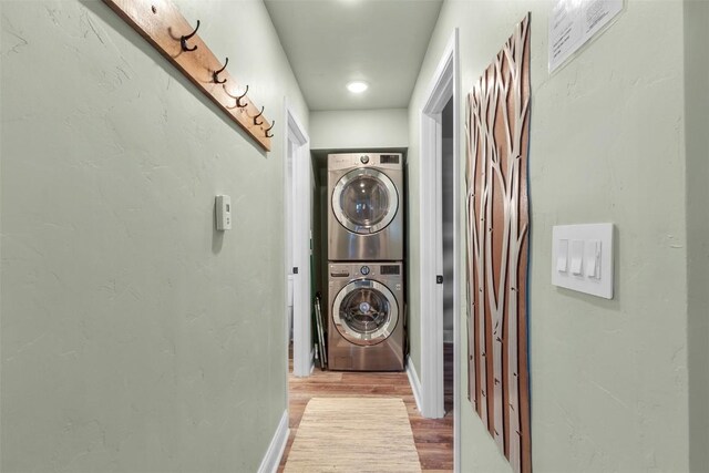 laundry area with light hardwood / wood-style flooring and stacked washer and clothes dryer