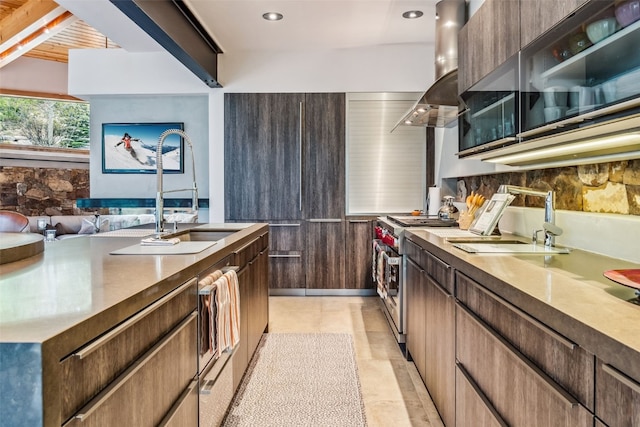 kitchen featuring tasteful backsplash, island range hood, sink, and range with two ovens