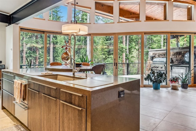 kitchen featuring a kitchen island with sink, sink, a healthy amount of sunlight, and lofted ceiling