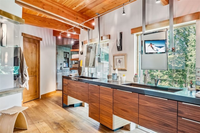 kitchen featuring beam ceiling, light hardwood / wood-style flooring, wood ceiling, and sink