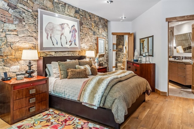 bedroom with ensuite bath and light wood-type flooring