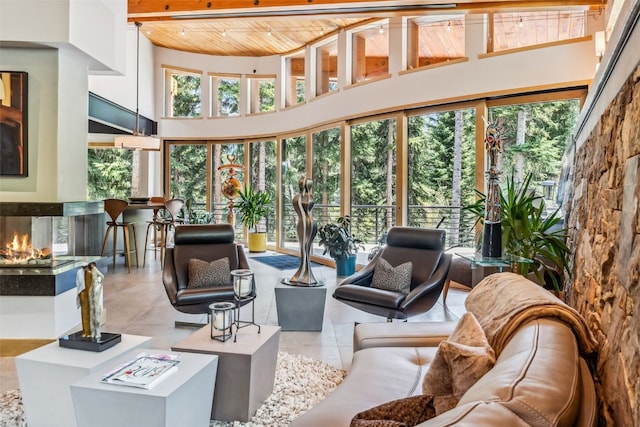 sunroom featuring a multi sided fireplace, wooden ceiling, and a wealth of natural light