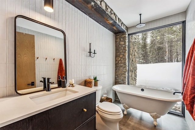 bathroom featuring toilet, a bathtub, tile walls, concrete flooring, and vanity