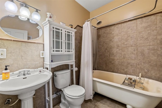 bathroom featuring tile patterned flooring, tile walls, toilet, and shower / bath combo