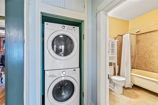 washroom with tile patterned flooring, stacked washer / dryer, and laundry area