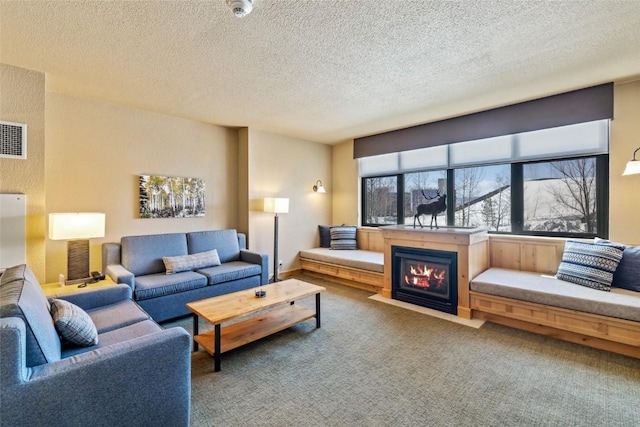 carpeted living room with visible vents, a fireplace with flush hearth, and a textured ceiling