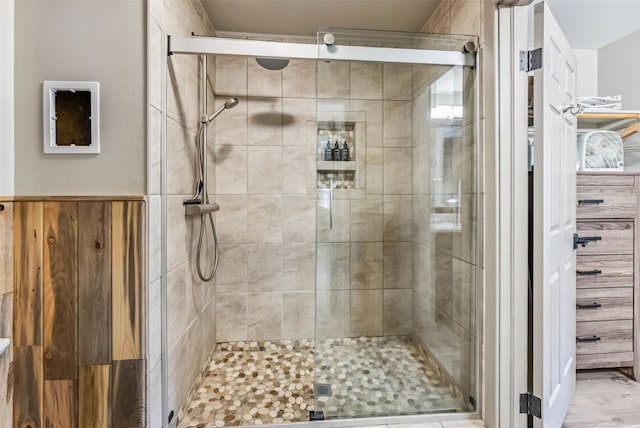 bathroom featuring a shower with door and wooden walls