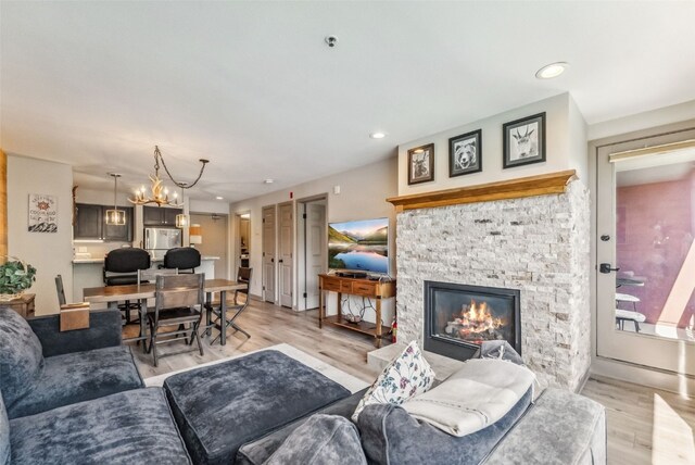 living room featuring a fireplace, light hardwood / wood-style floors, an inviting chandelier, and wood walls