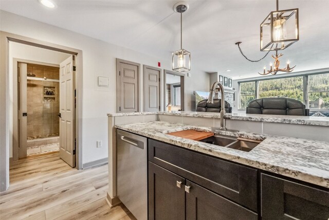 kitchen featuring stainless steel dishwasher, light stone counters, sink, light hardwood / wood-style flooring, and hanging light fixtures