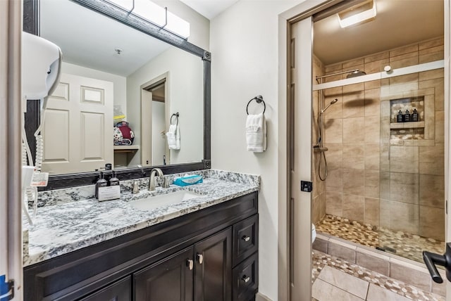 bathroom with tile patterned flooring, vanity, and walk in shower