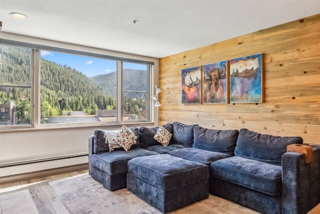 living room featuring wood walls, a mountain view, a baseboard radiator, and light wood-type flooring