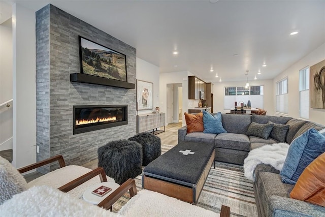 living area featuring recessed lighting, a tiled fireplace, and light wood finished floors