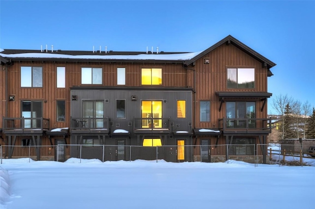 snow covered rear of property featuring a fenced front yard