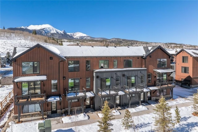 snow covered back of property with a mountain view and a residential view