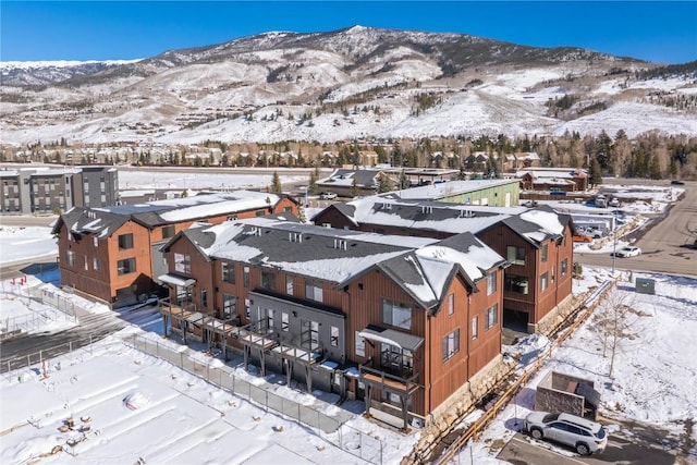 snowy aerial view featuring a residential view and a mountain view