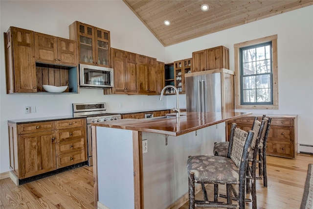 kitchen featuring light hardwood / wood-style flooring, wooden ceiling, a kitchen breakfast bar, stainless steel appliances, and a kitchen island with sink