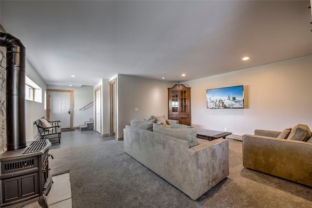 living room with a baseboard heating unit, a wood stove, and carpet flooring