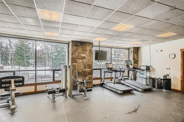 exercise room with a healthy amount of sunlight and a drop ceiling