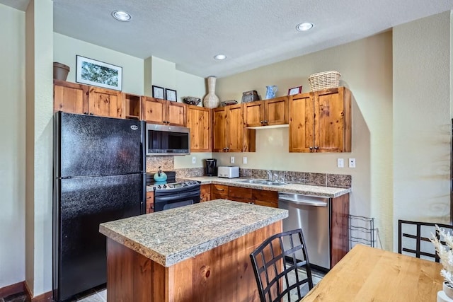 kitchen featuring sink, a kitchen island, stainless steel appliances, a textured ceiling, and a kitchen bar