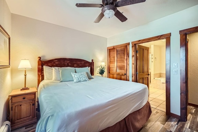 bedroom with connected bathroom, a baseboard heating unit, and ceiling fan