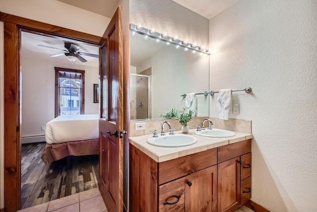 bathroom featuring walk in shower, tile patterned floors, baseboard heating, vanity, and ceiling fan