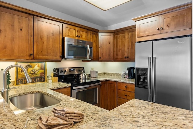 kitchen with light stone counters, stainless steel appliances, and sink