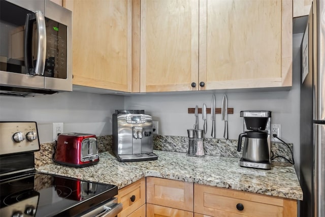 kitchen featuring light brown cabinets, light stone countertops, and stainless steel appliances