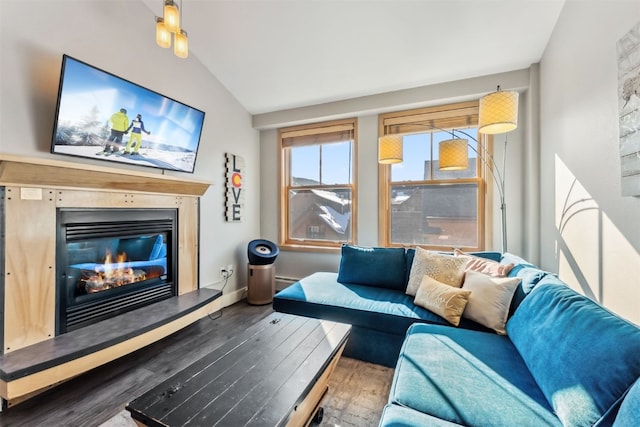 living area with baseboards, wood finished floors, a glass covered fireplace, and vaulted ceiling