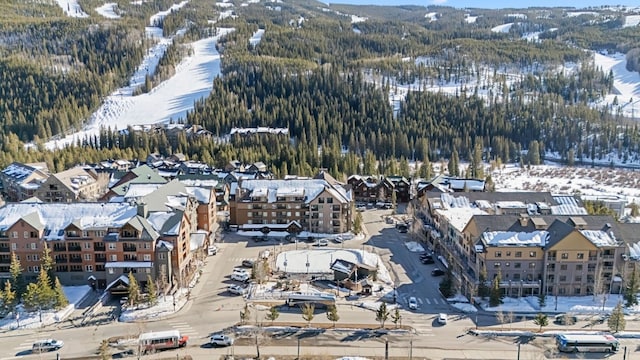 snowy aerial view with a mountain view and a residential view