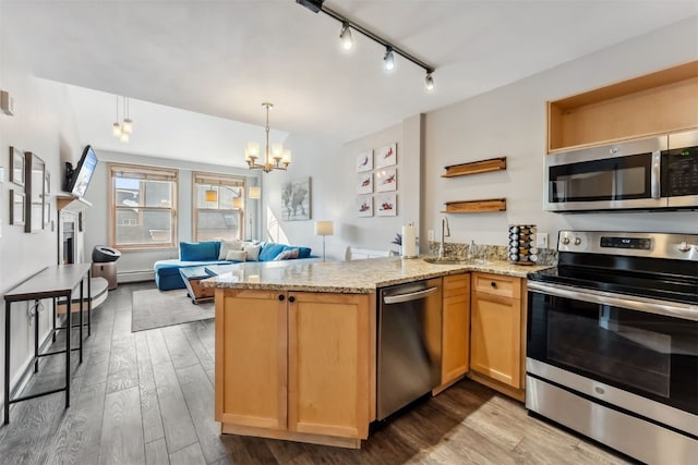 kitchen featuring open shelves, a peninsula, a sink, appliances with stainless steel finishes, and light wood-type flooring