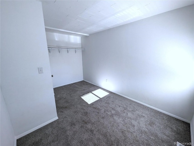 unfurnished bedroom with dark carpet and a closet