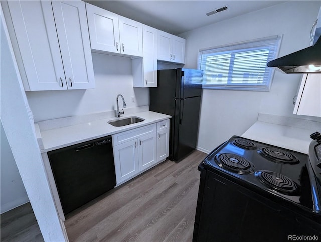 kitchen featuring exhaust hood, white cabinetry, black appliances, and sink