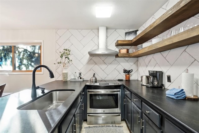 kitchen featuring wall chimney exhaust hood, stainless steel range oven, sink, and tasteful backsplash