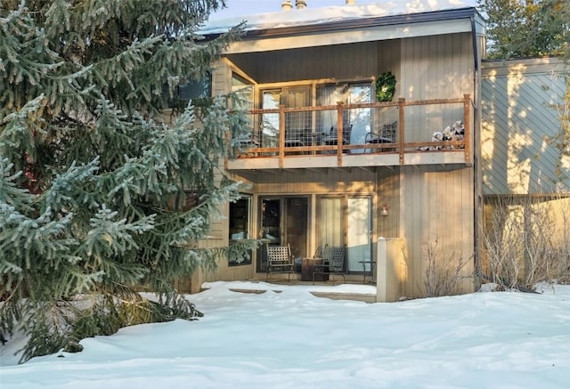 snow covered rear of property with a balcony