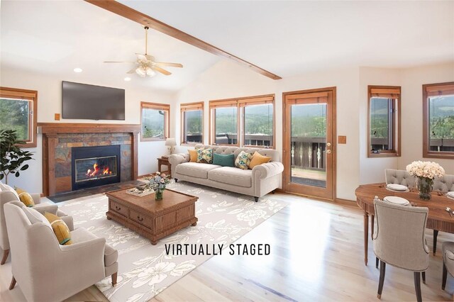 living room with a tile fireplace, lofted ceiling with beams, ceiling fan, and a healthy amount of sunlight