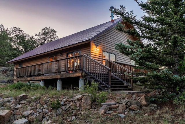 back house at dusk featuring a wooden deck