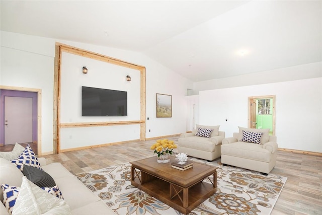 living room featuring lofted ceiling and light hardwood / wood-style flooring