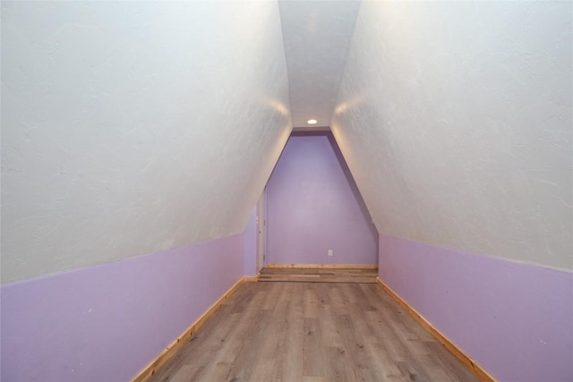 additional living space featuring lofted ceiling and light hardwood / wood-style flooring