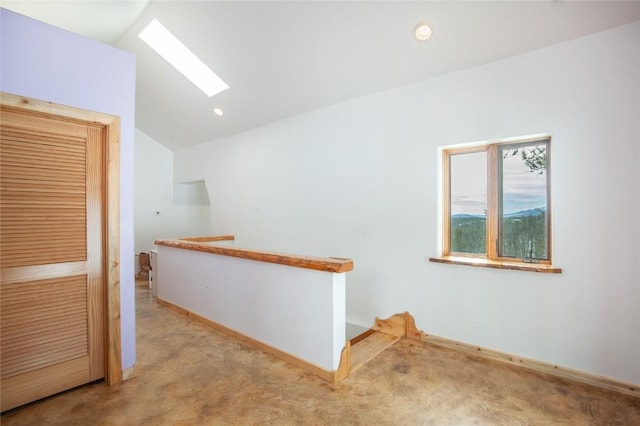 hall with light colored carpet and vaulted ceiling with skylight