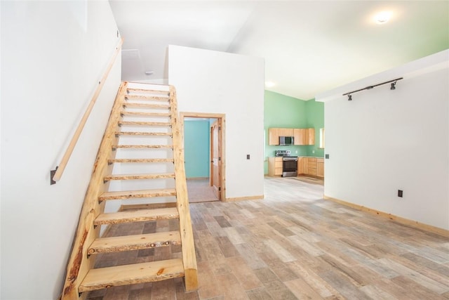 stairway with lofted ceiling, hardwood / wood-style flooring, and track lighting