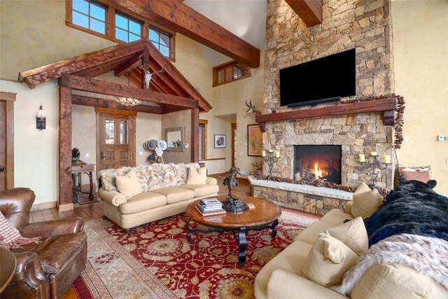 living room featuring hardwood / wood-style flooring, beam ceiling, a fireplace, and a high ceiling