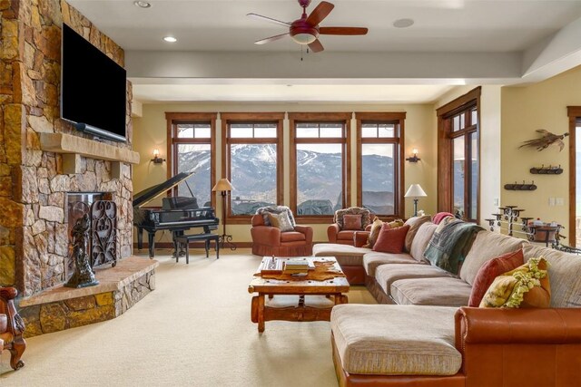 living room featuring carpet flooring, a stone fireplace, and ceiling fan