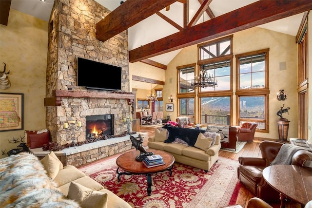 living room featuring light wood-type flooring, high vaulted ceiling, a notable chandelier, beamed ceiling, and a stone fireplace