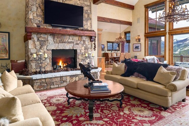 living room featuring a mountain view, beam ceiling, high vaulted ceiling, an inviting chandelier, and a fireplace