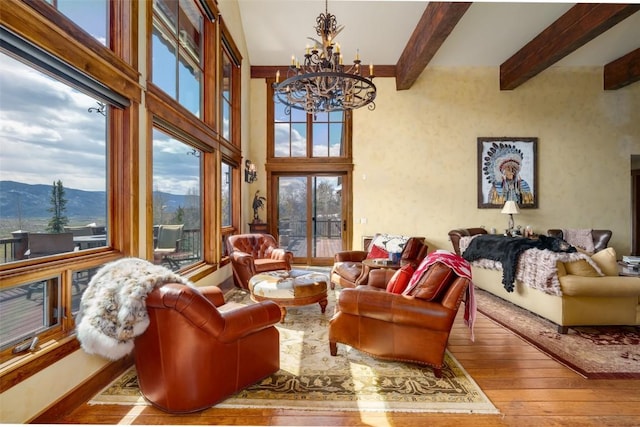 living room featuring a towering ceiling, wood-type flooring, an inviting chandelier, beamed ceiling, and a mountain view