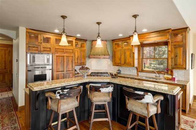 kitchen featuring a kitchen island, premium range hood, stainless steel appliances, and a breakfast bar area